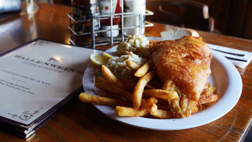 A delicious plate of fish and chips sits next to a stack of menus at Wellenwein's Hotel in East Aurora, near Buffalo NY.