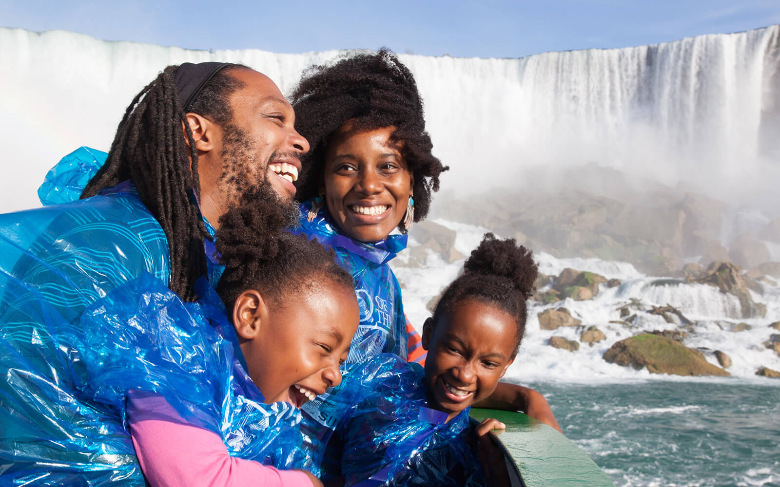 A family wearing ponchos admires Niagara Falls from a boat