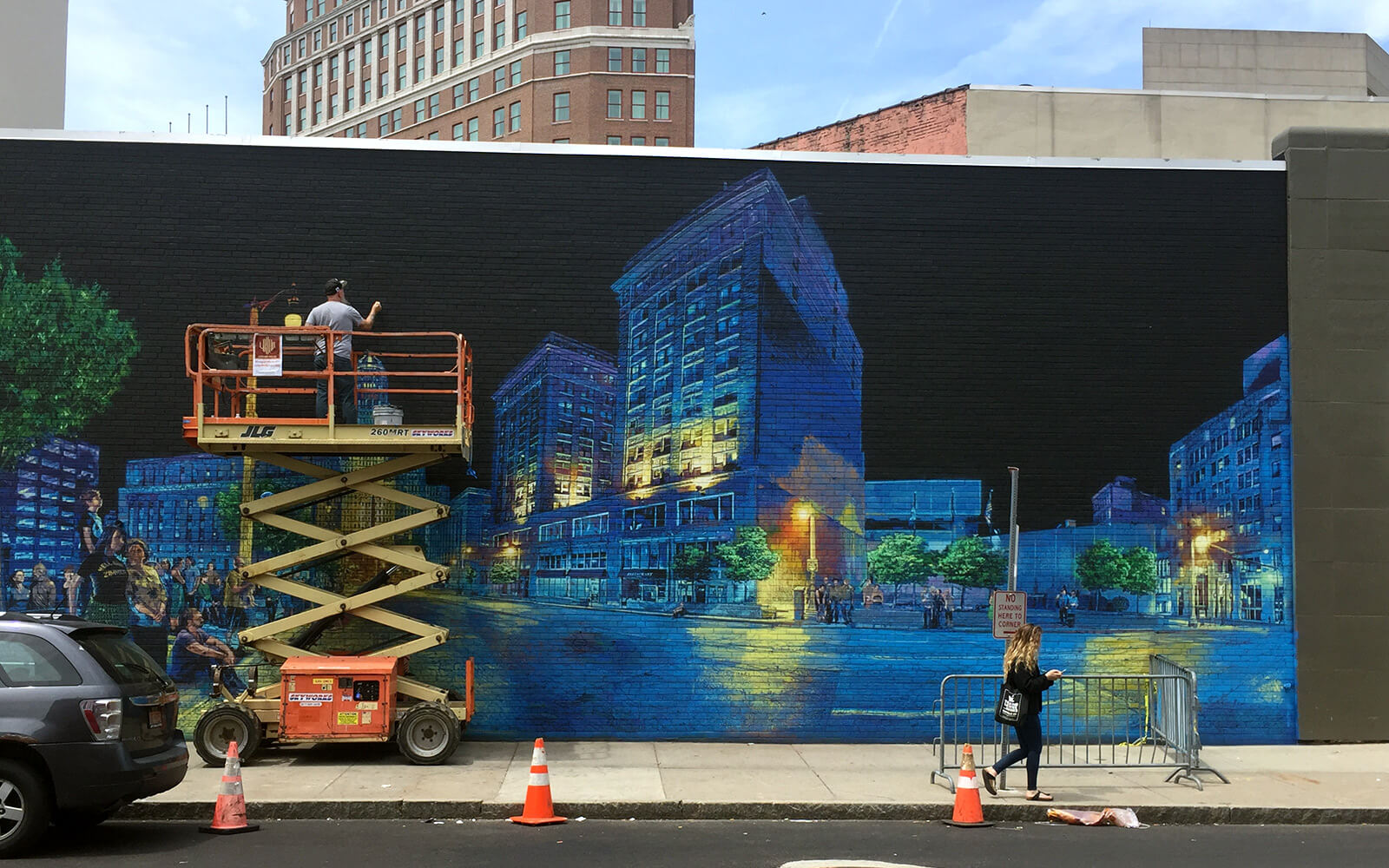 An artist adds finishing touches to a mural showcasing Buffalo's downtown