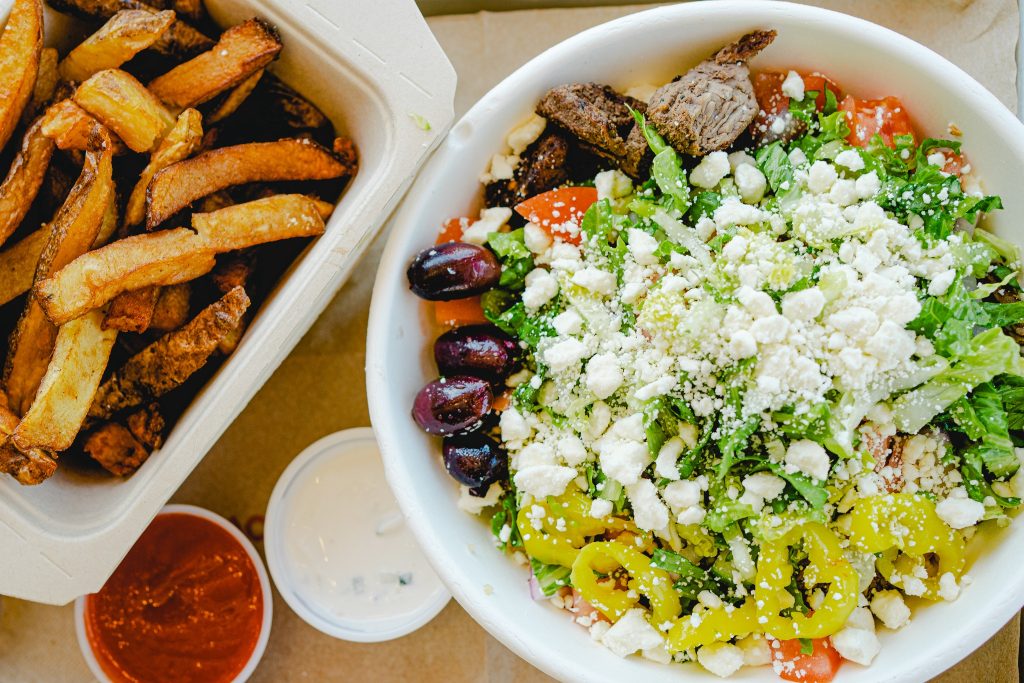 A Greek salad bowl and French fries