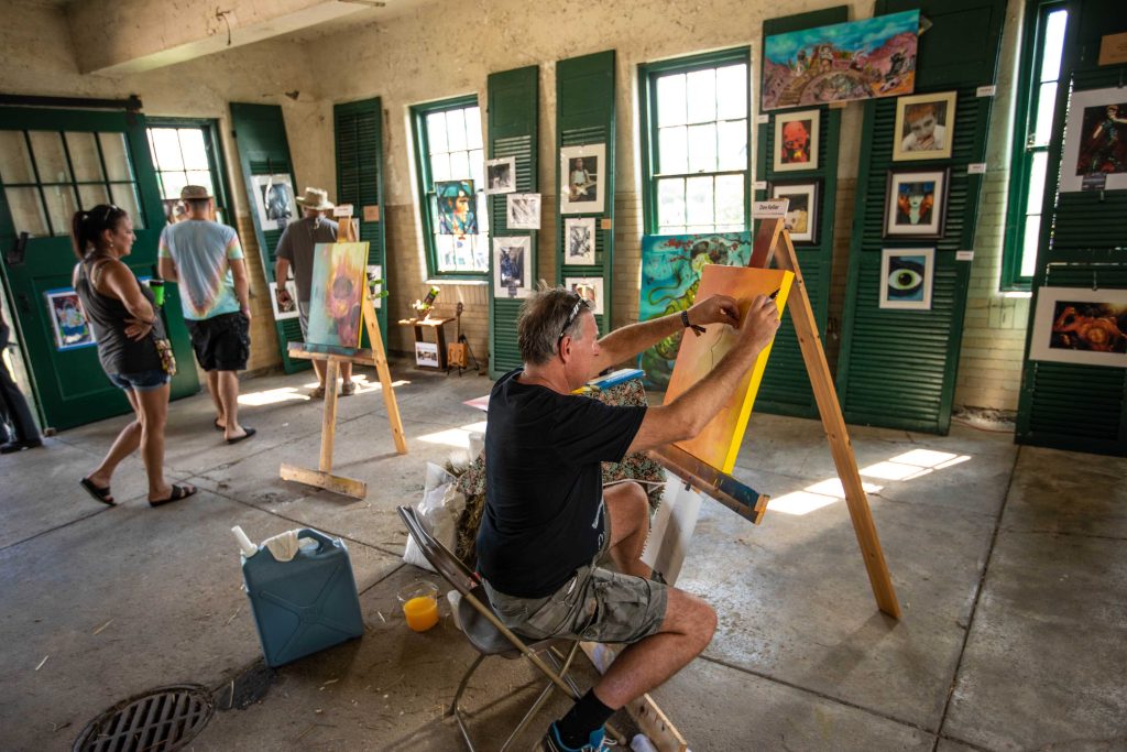 A photo of an artist painting within the stables of Knox Farm State Park at Borderland Music + Arts Festival.
